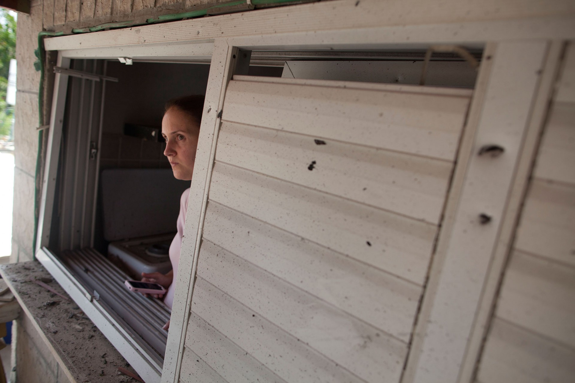 An Israeli woman inspects an Israeli home allegedly hit by a Hamas rocket on July 22, 2014 in Yahud south to Tel Aviv, Israel.